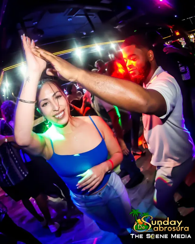 Partners dancing under colorful lights at Sunday de Sabrosura